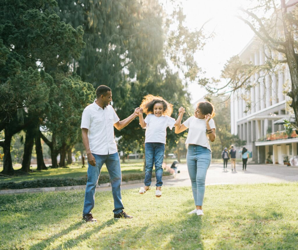 Joyful family enjoying a playful day at the park, embracing love and togetherness under the summer sun.