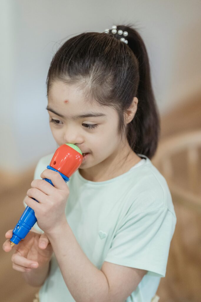 Young girl with Down Syndrome joyfully holding a colorful toy microphone indoors.